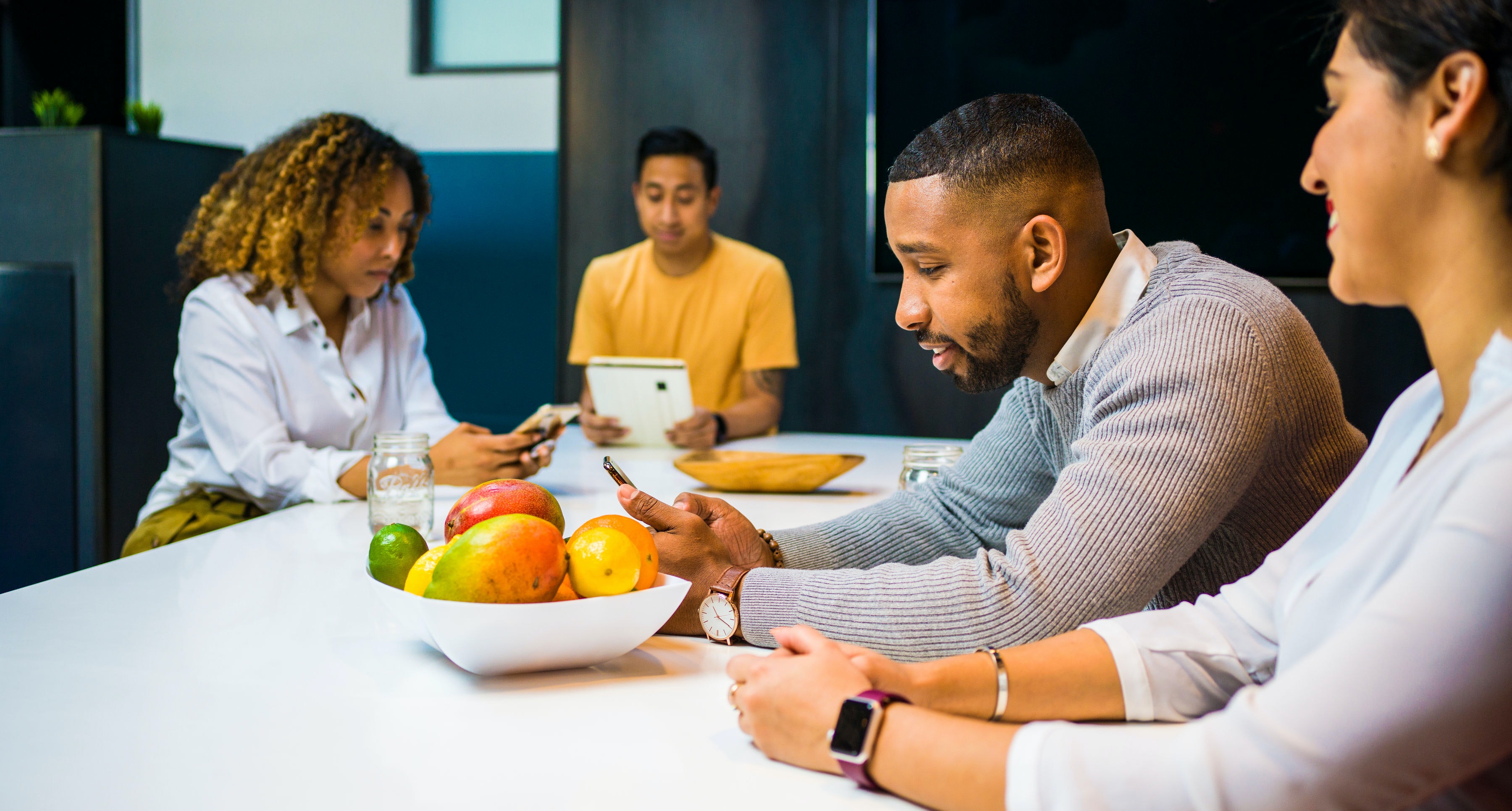 Employees at table discussing mental wellbeing for remote employees