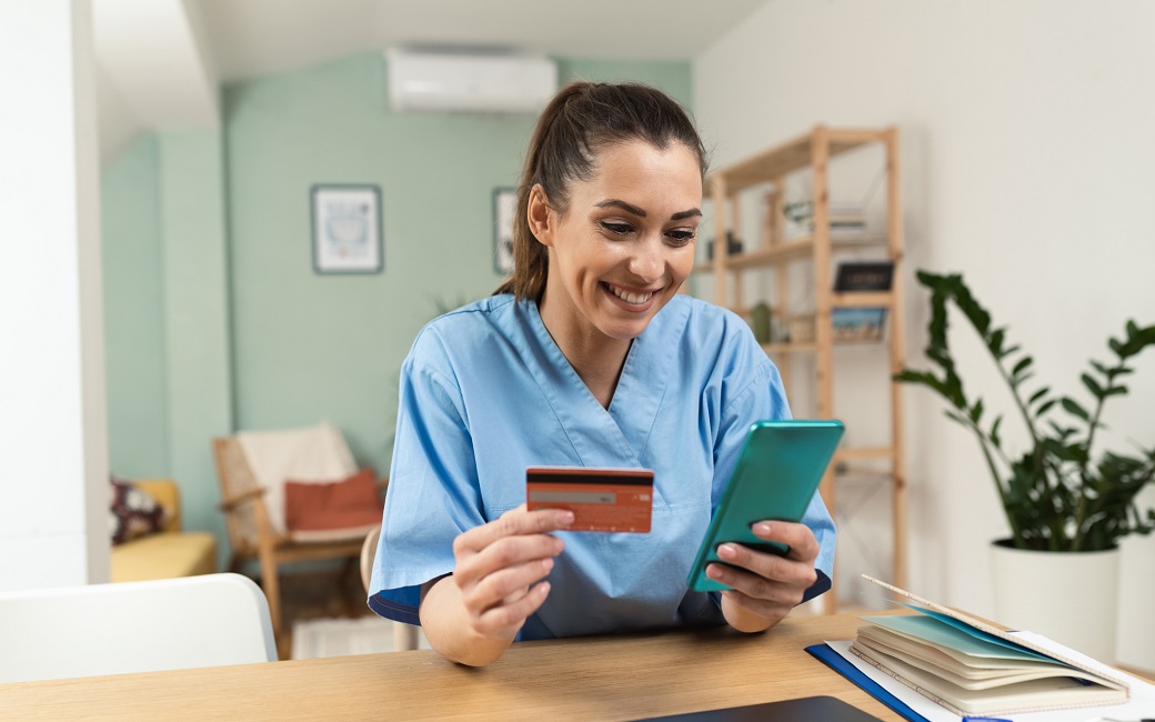 Hospital staff person holding a phone and credit card enjoying their corporate discount program benefits.
